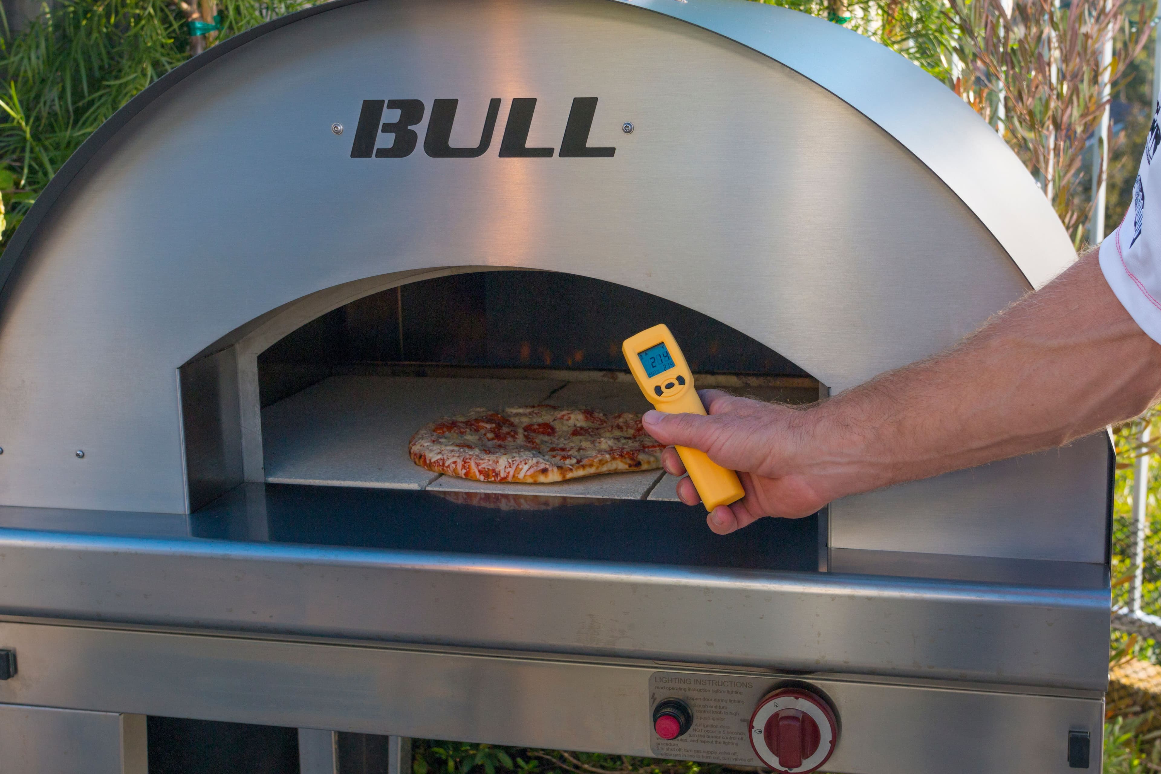 Premium American-made built-in grill in polished 304 stainless with hood open, mounted into a custom outdoor kitchen chase.